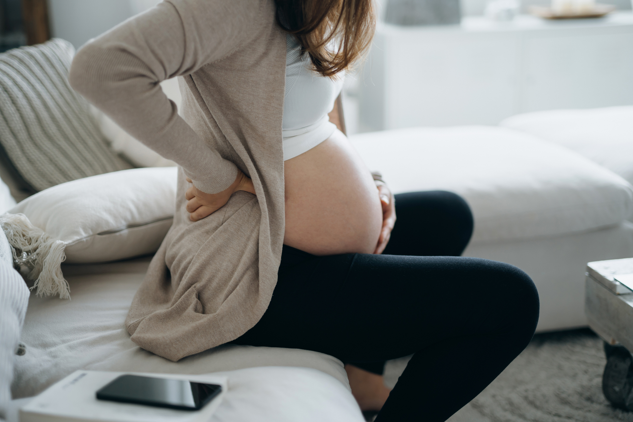 pregnant woman touching her belly and lower back